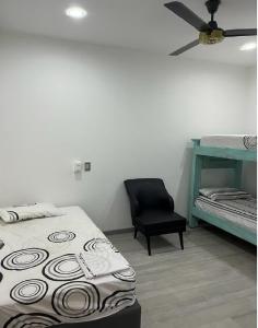ein Schlafzimmer mit einem Bett und einem schwarzen Stuhl in der Unterkunft Hermosa casa Ricaurte in Girardot