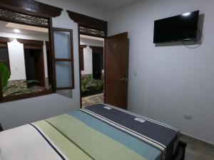 um quarto com uma cama e uma televisão de ecrã plano em HOTEL COLONIAL em Buga