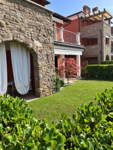 a stone house with white curtains in a yard at Appartamento Emerald in Sirmione