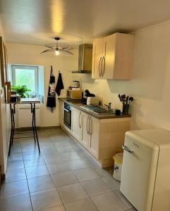 a kitchen with white cabinets and a tile floor at Duplex en plein centre-ville in Morestel