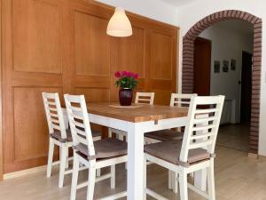 a dining room table with white chairs and a vase with flowers at Dallacker 55 FeWo 2 in Cuxhaven