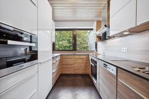 a kitchen with wooden cabinets and a window at EXQUIS Kunstvolles Luxusapartment I Designmöbel I Balkon I Homeoffice I Parken I Netflix in Böblingen