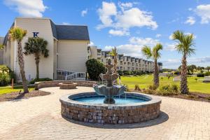 einen Brunnen vor einem Gebäude mit Palmen in der Unterkunft A Place at the Beach III, a VRI resort in Atlantic Beach