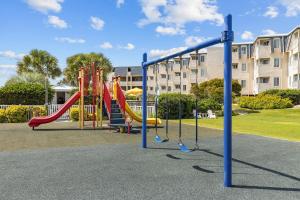 einen Spielplatz mit einer roten Rutsche und einer Rutsche in der Unterkunft A Place at the Beach III, a VRI resort in Atlantic Beach