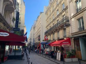 eine Stadtstraße mit Gebäuden und Menschen, die eine Straße hinuntergehen in der Unterkunft Paris rare pearl 5e Notre Dame Saint Michel in Paris