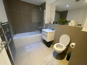 a bathroom with a toilet and a tub and a sink at 1 Bedroom Flat in London CB46 in Croydon