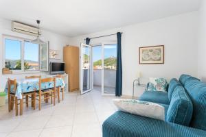 a living room with a blue couch and a table at Family friendly apartments with a swimming pool Seget Vranjica, Trogir - 14409 in Donji Seget