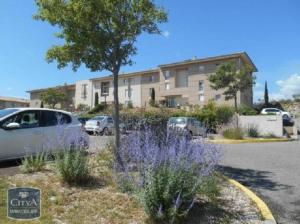 - un parking avec des fleurs violettes en face d'un bâtiment dans l'établissement Appartement les Angles clim WiFi, aux Angles (Gard)