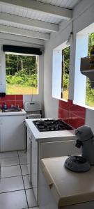 una cucina con piano cottura e lavandino e 2 finestre di Weston a Deshaies