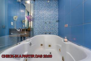 a white bath tub in a bathroom with blue tiles at Motel Porto dos Casais in Porto Alegre