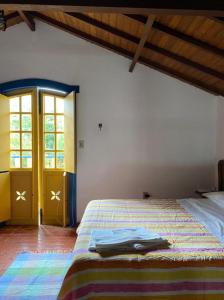 a bedroom with a bed with a colorful blanket at Arraial Velho Pousada Tematica in Tiradentes