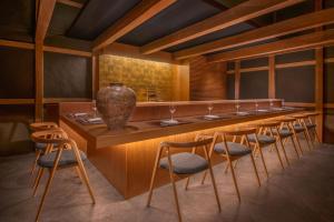 Shisui, a Luxury Collection Hotel, Nara في نارا: مطعم مع بار طويل مع كراسي و مزهرية