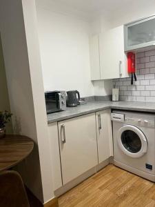 a kitchen with a washing machine and a microwave at Apt 1 prime central Location close cathedral in Norwich