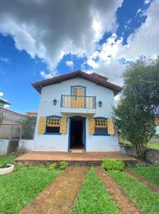a white house with a porch and a balcony at Arraial Velho Pousada Tematica in Tiradentes