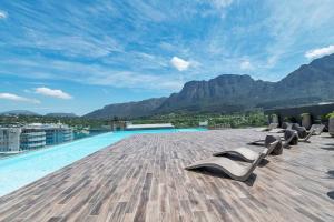 a pool with lounge chairs on the roof of a building at Rooftop with breathtaking views of Table Mountain. in Cape Town