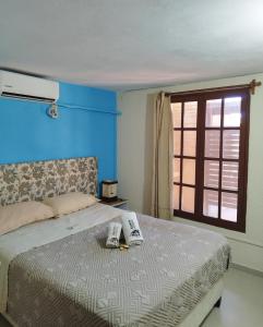 a bedroom with a bed with a blue wall and a window at Aparts Complejo Arinos in Aguas Dulces