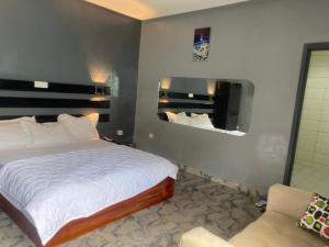 a bedroom with a bed and a mirror and a chair at Sunrise Center Bonapriso - 102 in Douala