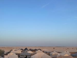 a group of tents in a desert with people in the background at Luxury Camp Dunes Insolites Sabria in Sabria