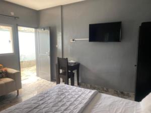 1 dormitorio con 1 cama y TV en la pared en Sunrise Center Bonapriso - 102, en Douala