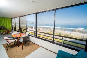 a room with a table and chairs and a view of the ocean at Departamento grande frente a playa Cavancha in Iquique