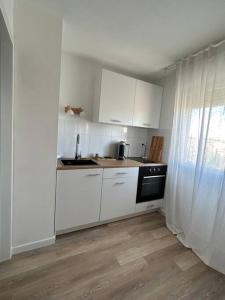 a kitchen with white cabinets and a black stove at Romantique Room in Muret +2 photos