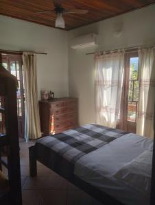 a bedroom with a bed and a dresser and windows at Green House Jabaquara in Paraty