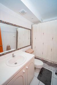 een badkamer met een wastafel, een toilet en een spiegel bij Departamento grande frente a playa Cavancha in Iquique