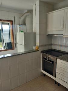 a white kitchen with a stove and a refrigerator at PRIME ALOJAMNETOS 01 in Gondomar