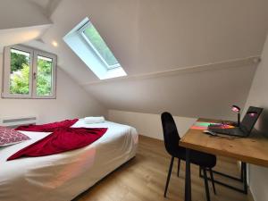 a bedroom with a bed and a desk with a laptop at Le Bellevue - Beaux appartements avec vue splendide in Palaiseau