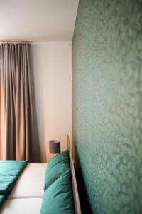 - une chambre avec un lit et un mur vert dans l'établissement Green46, à Meerbusch