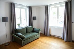 a living room with a green couch and two windows at Green46 in Meerbusch