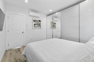 Un dormitorio blanco con una cama blanca y una puerta. en Miracle Mile Chic 1 BR Bungalow Apt Parking Unit 2, en Los Ángeles