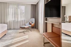 a hotel room with a chair and a television at Courtyard by Marriott Dortmund in Dortmund