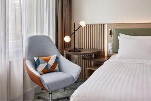 ein Schlafzimmer mit einem Bett und einem Stuhl mit einem Kissen in der Unterkunft Courtyard by Marriott Dortmund in Dortmund