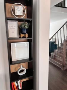 a book shelf with a clock and books at Modern & Cozy Kawartha Getaway in Kawartha Lakes