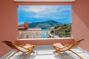 a balcony with two chairs and a large window at Villa Kamelicina in Vinišće