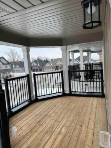 a porch with a wooden deck with black railing at Modern & Cozy Kawartha Getaway in Kawartha Lakes