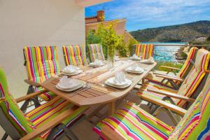 a wooden table with colorful chairs on a balcony at Villa Kamelicina in Vinišće