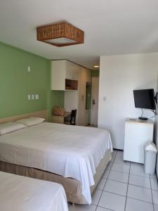 a bedroom with two beds and a television in it at Gran Lençóis Flat Residence in Barreirinhas