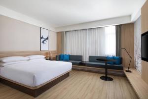 a bedroom with a bed and a couch and a television at Fairfield by Marriott Shanghai Pudong Central in Shanghai