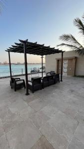 a seating area with a large umbrella and the beach at درة العروس فيلا فاخره بمسبح داخلي in Durat Alarous