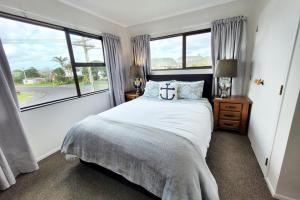 ein Schlafzimmer mit einem Bett und einem großen Fenster in der Unterkunft Hosts on the Coast Whiti Te Ra Sunrise in Whitianga