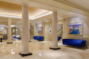 a lobby with columns and a blue couch at The College Green Dublin Hotel, Autograph Collection in Dublin