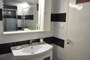 ein Badezimmer mit einem weißen Waschbecken und einem Spiegel in der Unterkunft Zennova #5 Antigonidon Square in Thessaloniki