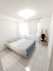 um quarto branco com uma cama e uma janela em Verano Apart Ponta Negra em Natal