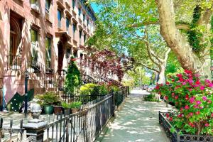 una calle con flores y una valla y edificios en Bright, airy, luxe hideaway”w” private backyard, en Brooklyn