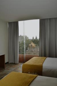 グアダラハラにあるHVH by Yaxchéのベッド2台と大きな窓が備わるホテルルームです。