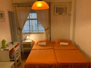 1 dormitorio con cama, escritorio y ventana en Quartos em Copacabana, en Río de Janeiro