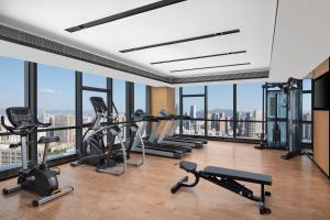 un gimnasio con cintas de correr y máquinas de ejercicio cardiovascular en una habitación con ventanas en Fairfield by Marriott Kunming Xinying, en Kunming