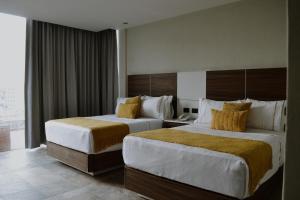 Habitación de hotel con 2 camas y ventana en HVH by Yaxché en Guadalajara
